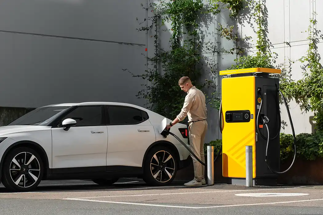 Man laddar sin vita polestar 2 vid en publik laddstation i Centrala Göteborg.